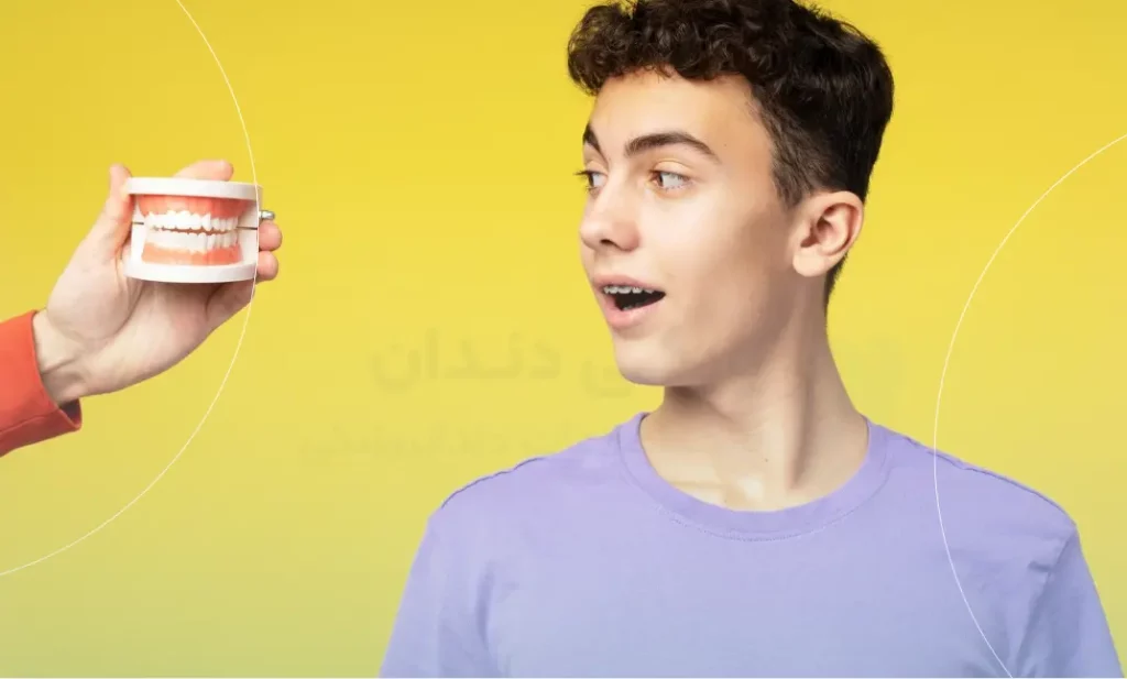 تصویری از یک جوان در حال مشاهده دندان مصنوعی